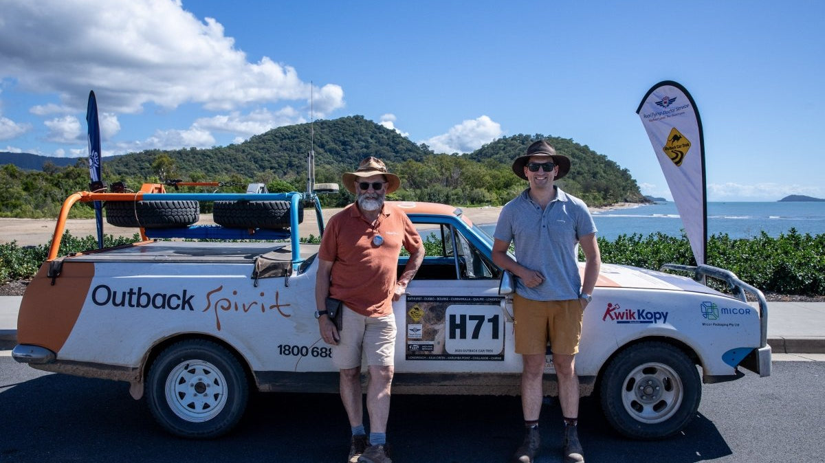 2 aussie blokes, a father and his son, standing in front of a car. Both dressed in different types of men's shorts