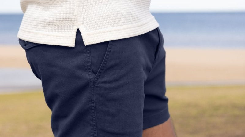 Man wearing navy shorts at the beach, close-up of fit and fabric