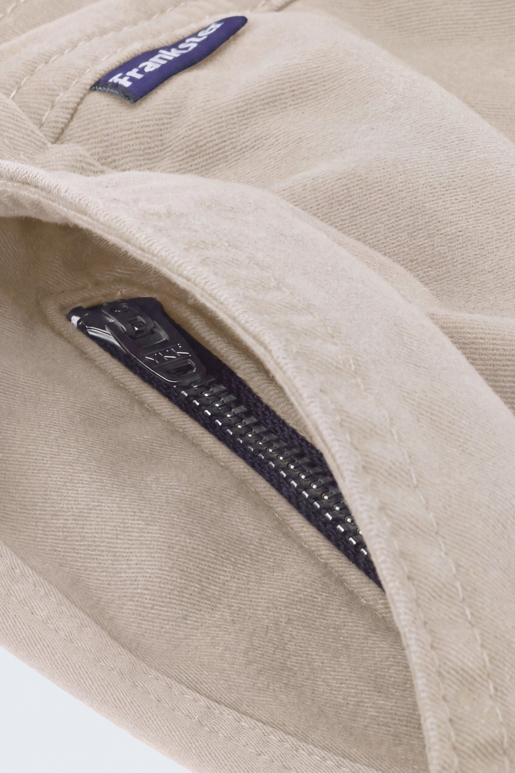 Close-up of beige men's shorts by Frankster featuring a soft fabric texture and a hidden black zip pocket from Shores * The Everydays collection.
