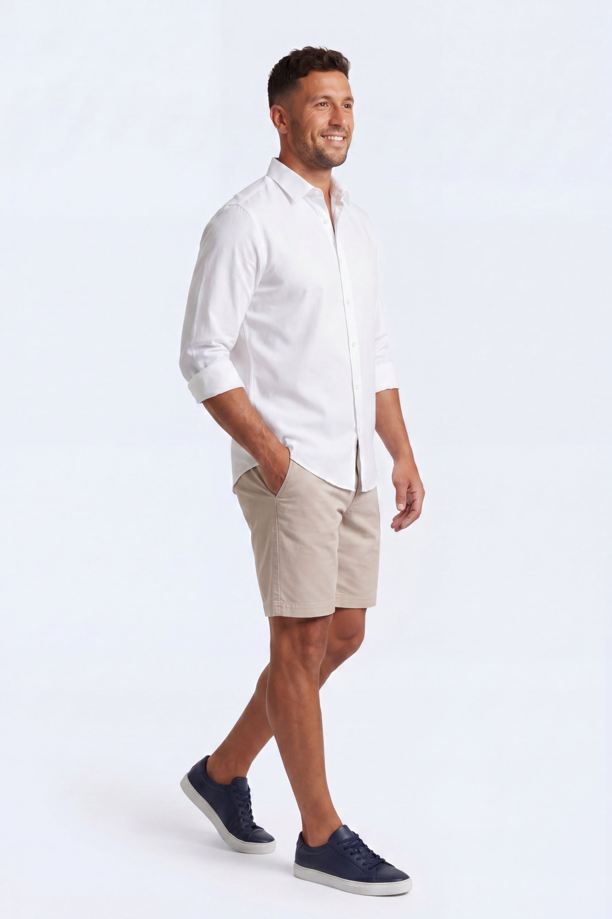 Man wearing beige Shores * The Everydays men's shorts by Frankster paired with a white shirt and navy sneakers, showcasing comfortable cotton fabric.