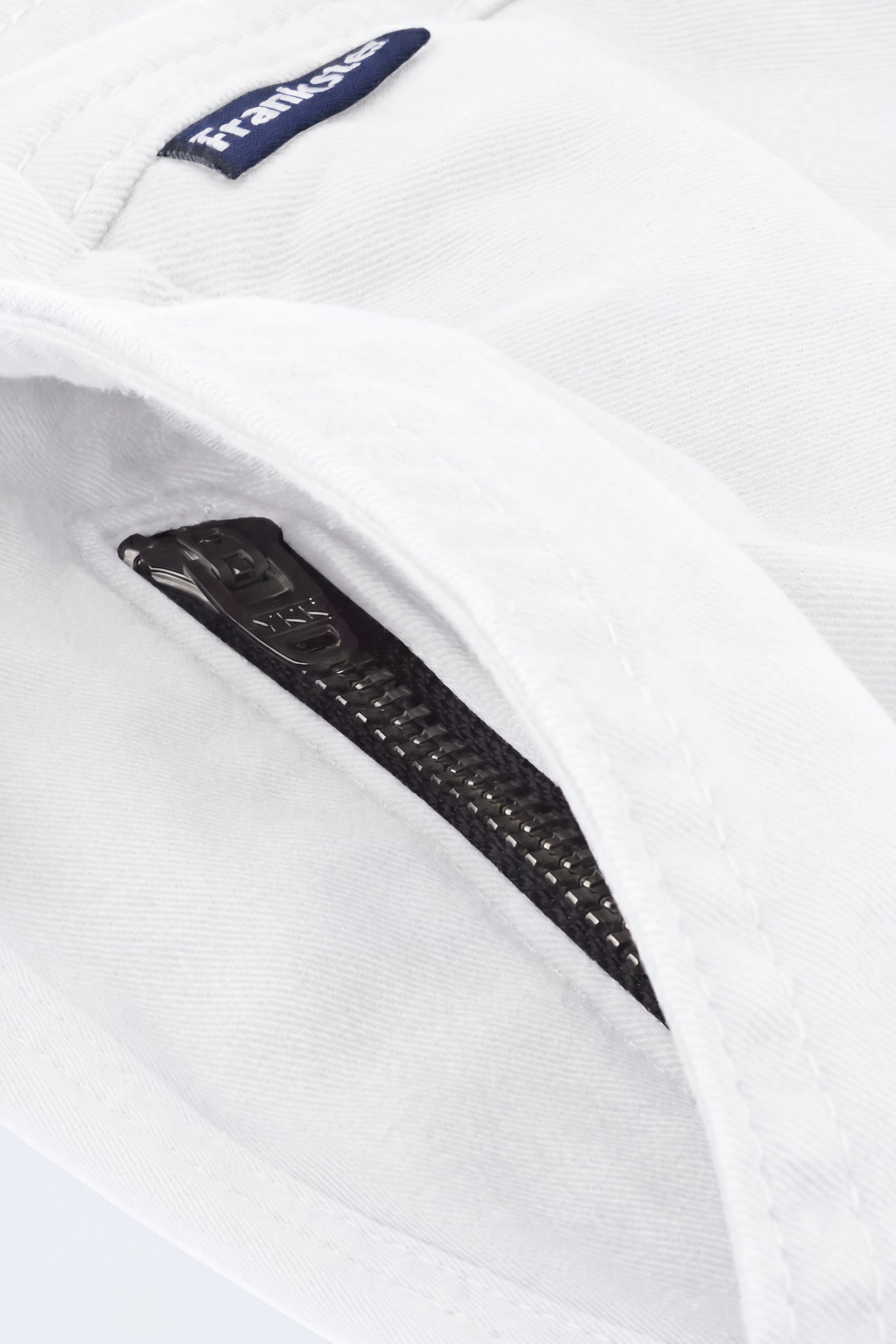 Close-up of white fabric men's shorts from Frankster featuring a black zipper pocket detail, highlighting comfort and premium material from Whitecaps * The Everydays.
