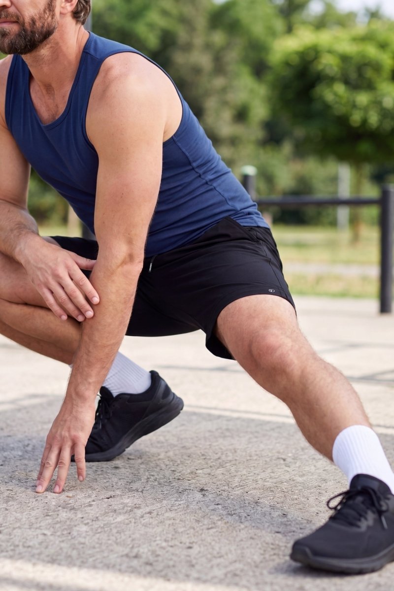 Frankster Midnights * The Sporties Men's Shorts in black fabric, model wearing versatile men's shorts during an outdoor stretch