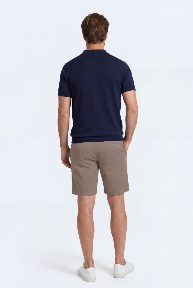 Man wearing taupe cotton men's shorts from Frankster's Nomads * The Everydays collection, paired with a navy shirt and white sneakers.