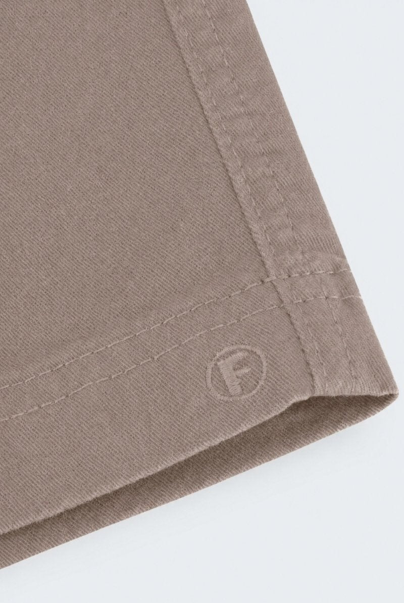 Close-up of taupe-colored men's shorts made from soft, durable fabric with neat stitching and subtle Frankster logo embossing, part of Nomads * The Everydays.