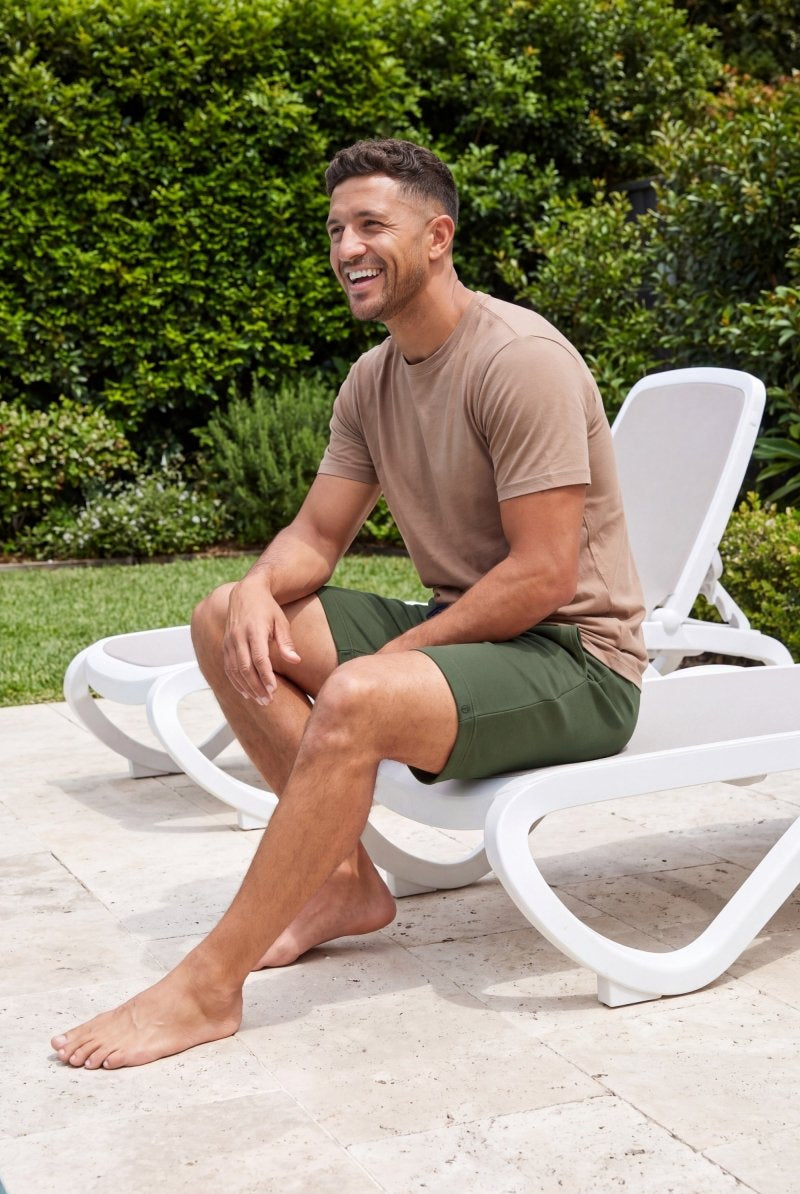 Frankster Rebels * The Comfies olive green Men's Shorts in soft textured fabric worn by a smiling man relaxing poolside