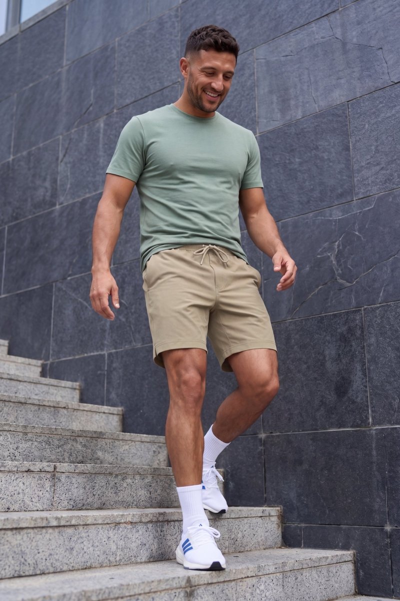 Frankster Sandbars * The Sporties Men's Shorts in beige woven fabric with a drawstring waist worn on stone steps
