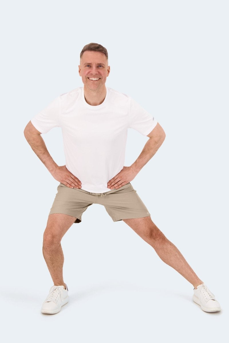 Frankster Sandbars * The Sporties Men's Shorts in beige fabric, shown on a man in a white tee during an active pose