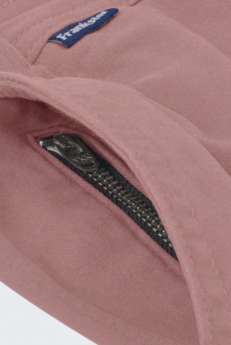 Close-up of dusty pink men's shorts fabric showing a black YKK zipper on a hidden pocket, designed by Frankster for Sundowners * The Everydays, highlighting soft, durable material ideal for comfortable wear.