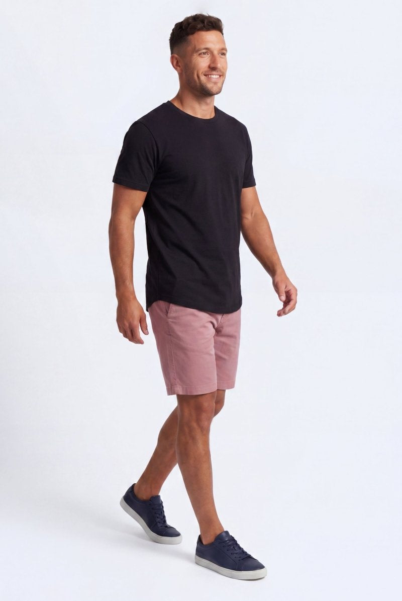 A smiling man wearing Frankster Sundowners * The Everydays men's shorts in a muted rose color, made from soft, comfortable fabric perfect for all-day wear.
