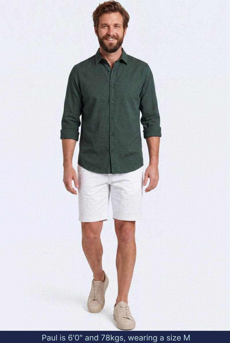 Man wearing white cotton blend Whitecaps * The Everydays men's shorts by Frankster paired with a dark green shirt and beige sneakers, showcasing comfortable and stylish men shorts.