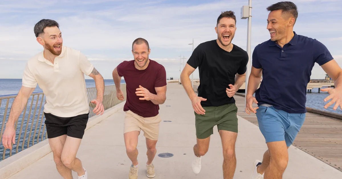 Four men running on a pier wearing casual men's shorts in black, beige, olive, and blue colors with light tops