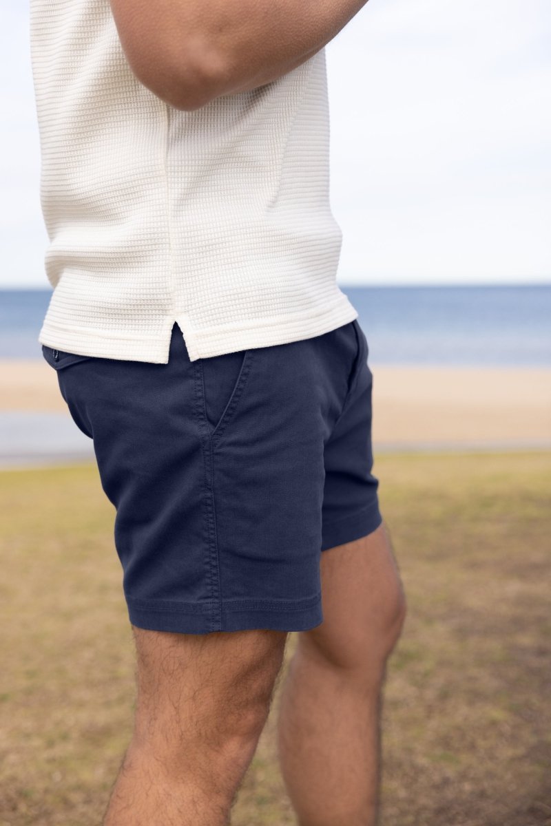 Man wearing navy shorts at the beach, close-up of fit and fabric