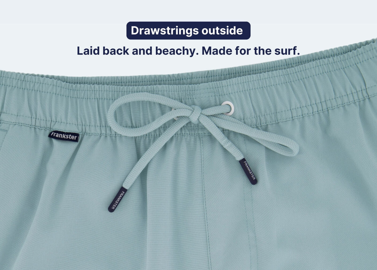 Light blue Men's Shorts in textured fabric with an elastic waistband and external white drawstrings for a beachwear look.