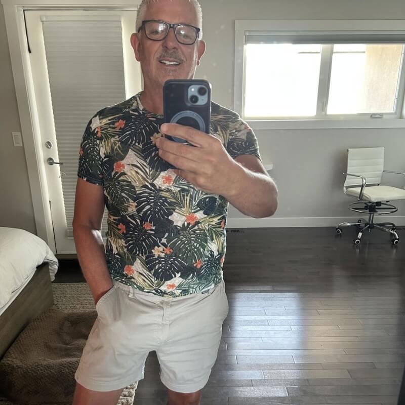 Man wearing light beige fabric Men's Shorts in a mirror selfie indoors