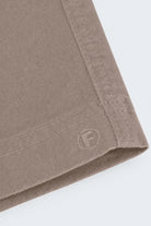 Close-up of taupe-colored men's shorts made from soft, durable fabric with neat stitching and subtle Frankster logo embossing, part of Nomads * The Everydays.