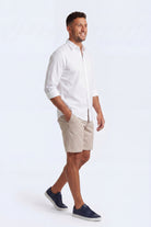Man wearing beige Shores * The Everydays men's shorts by Frankster paired with a white shirt and navy sneakers, showcasing comfortable cotton fabric.