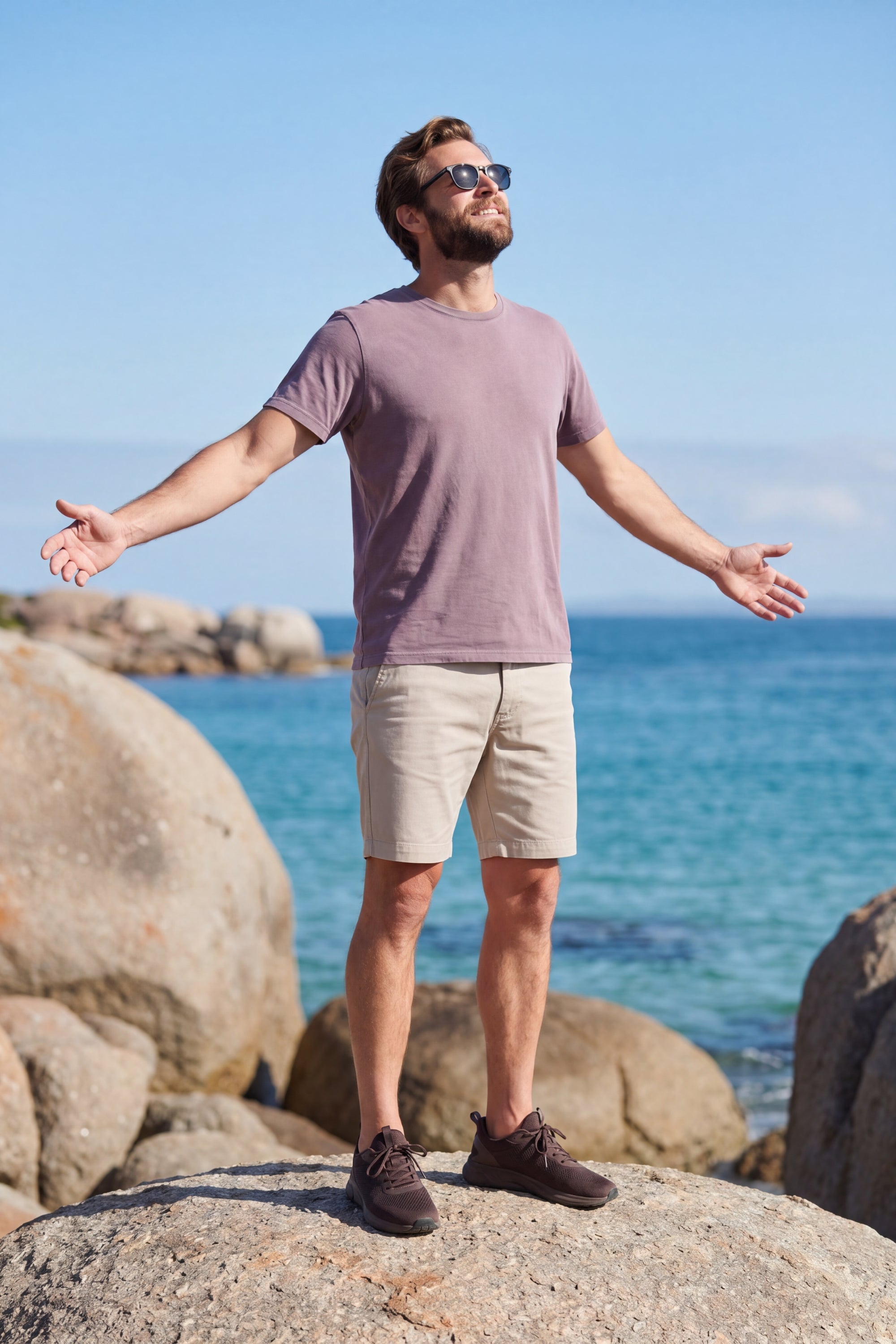 Man standing on a rock by the ocean wearing beige Shores * The Everydays men’s shorts by Frankster with a relaxed fit and soft fabric for all-day comfort.