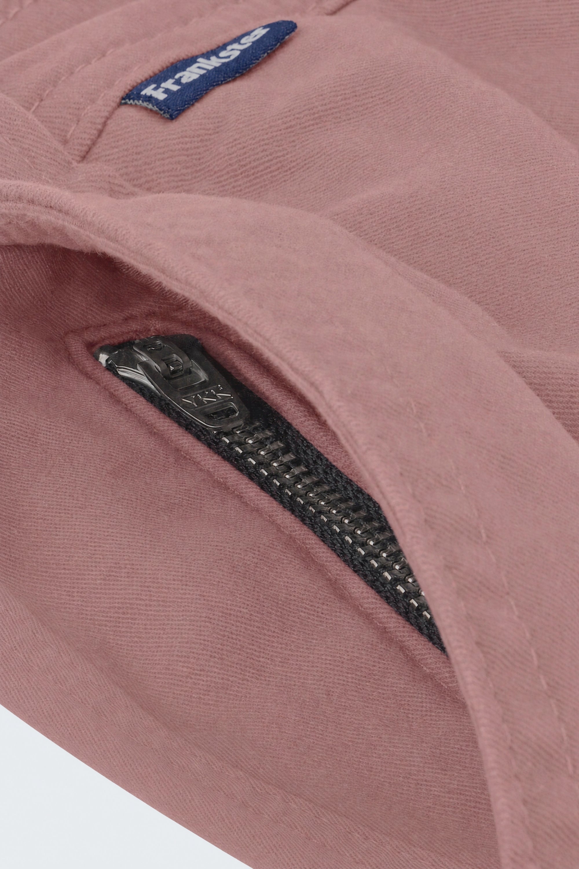 Close-up of dusty pink men's shorts fabric showing a black YKK zipper on a hidden pocket, designed by Frankster for Sundowners * The Everydays, highlighting soft, durable material ideal for comfortable wear.