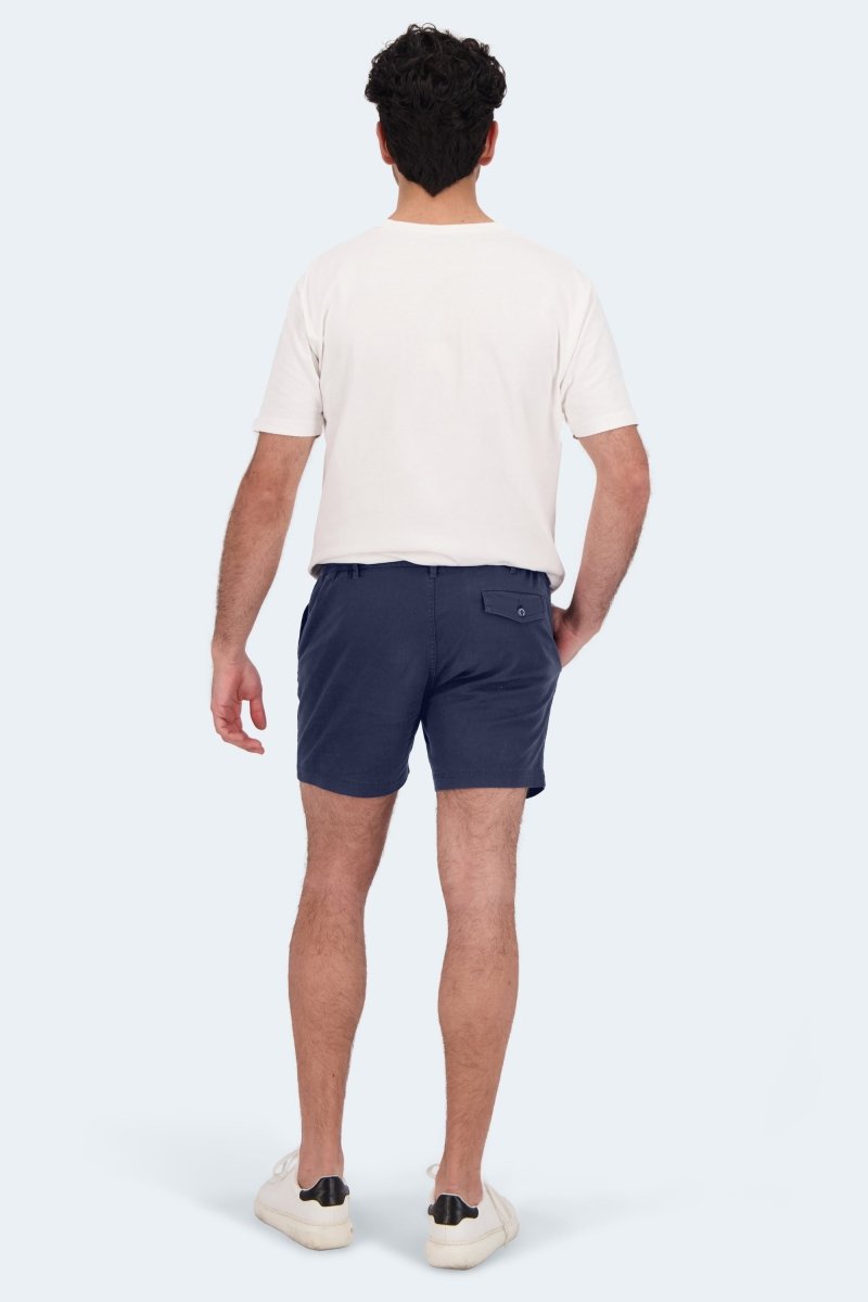 Man wearing navy blue Frankster Chillers * The Shorties men's shorts made from stretch cotton standing against light background