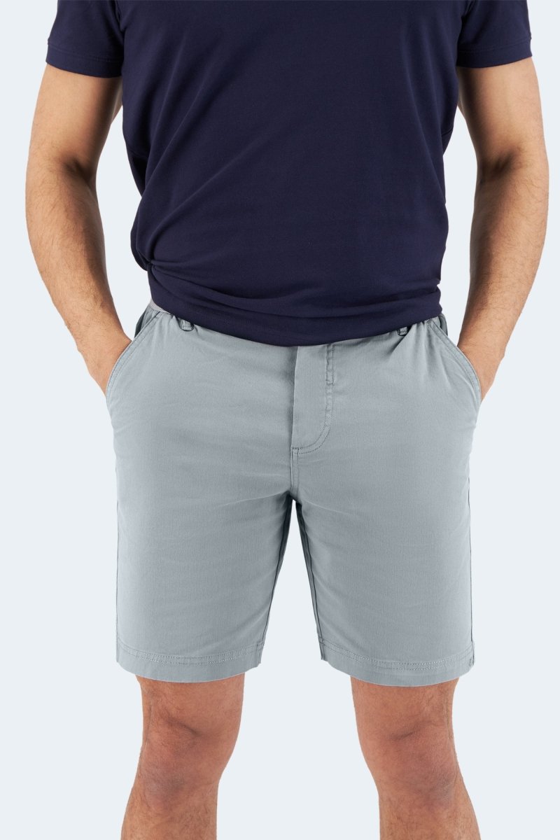 Man wearing Coastlines * The Everydays Frankster blue grey stretch cotton men's shorts with hands in pockets and navy shirt