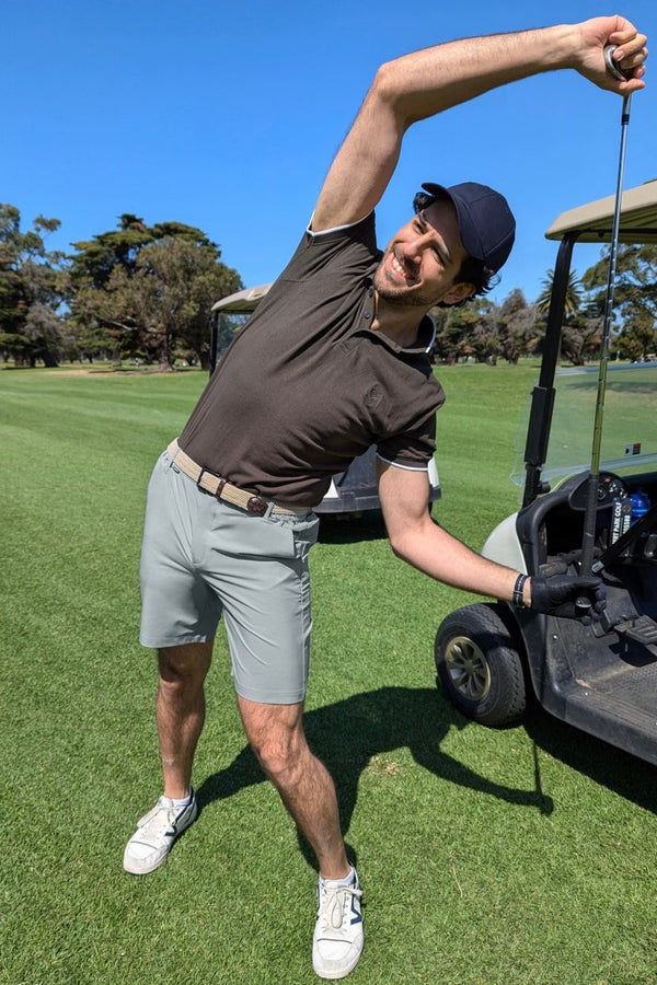 Man wearing Frankster Coastlines * The Actives blue grey lightweight men's shorts stretching by golf cart outdoors