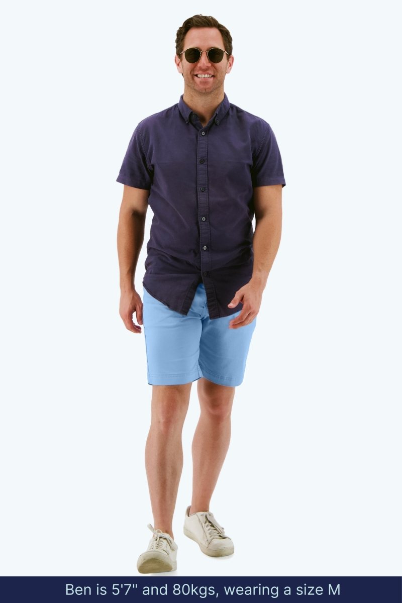 Man wearing Frankster Cruisers * The Everydays light blue stretch cotton men's shorts with navy short sleeve shirt and sneakers