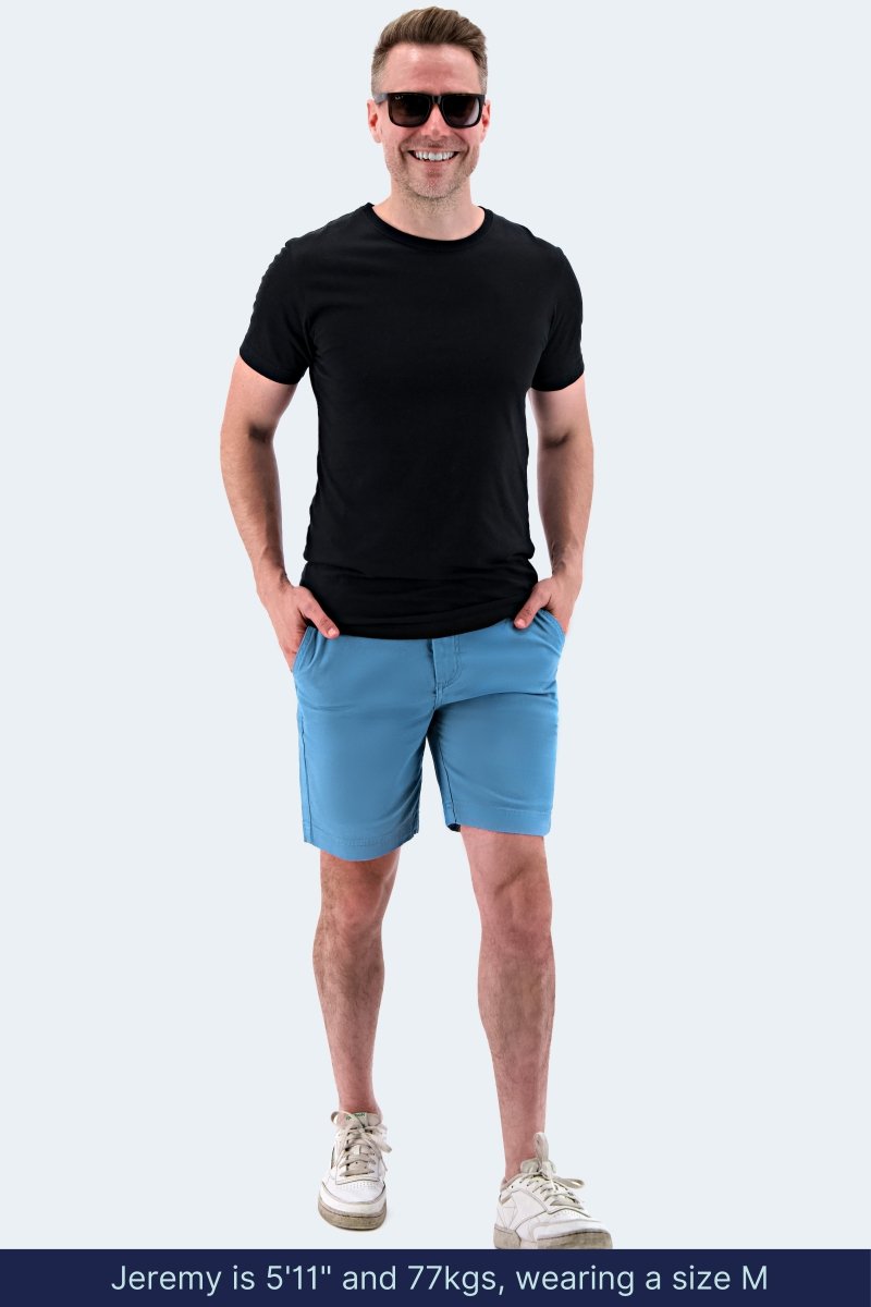 Man wearing Frankster Harbors * The Everydays mid blue stretch cotton men's shorts with a black t-shirt and sneakers