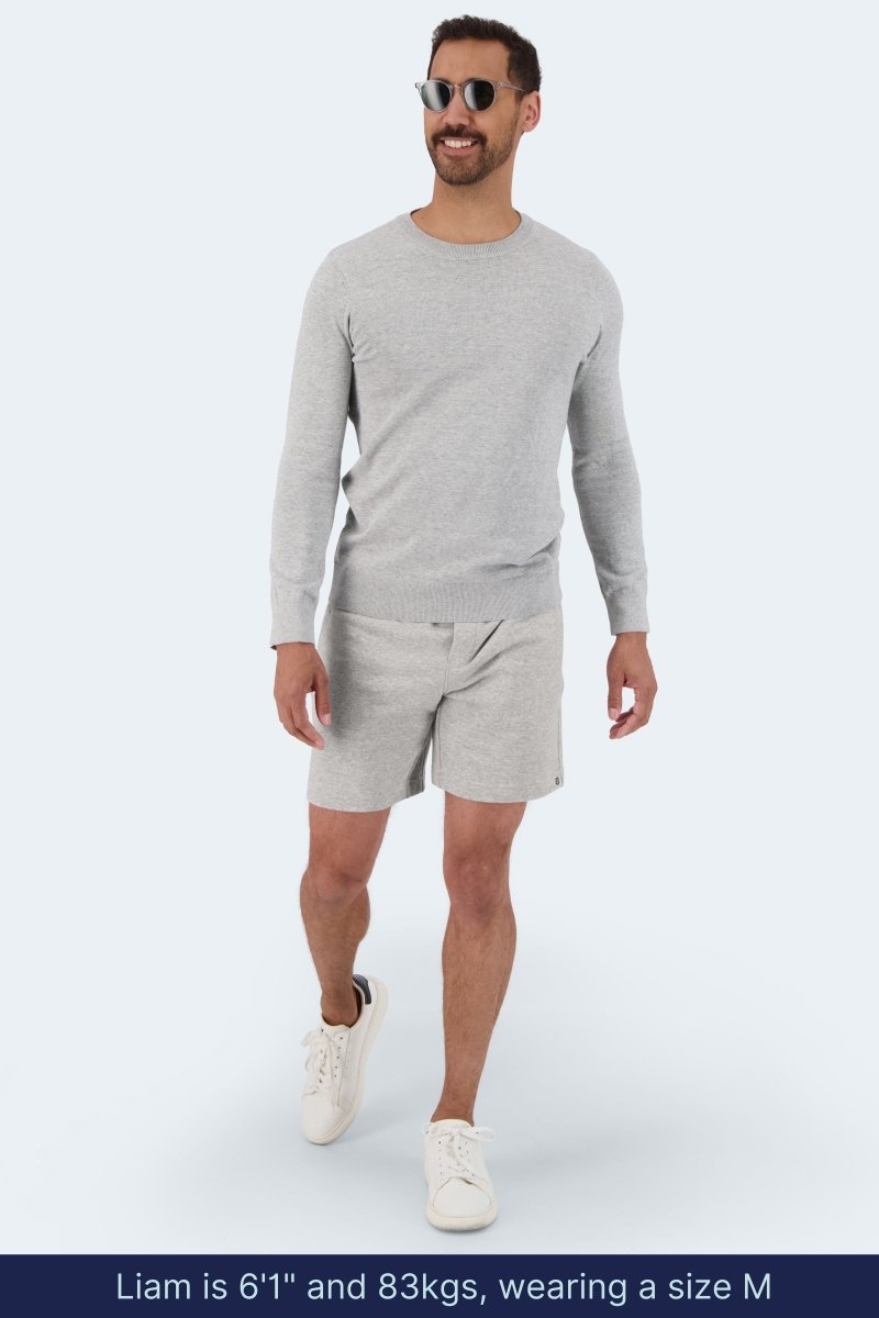 Man wearing light grey Frankster Lunars * The Comfies men's shorts and matching sweater with white sneakers walking outdoors