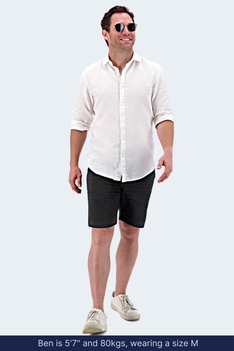 Man wearing black stretch cotton mid-length men's shorts from Midnights * The Everydays by Frankster with a white shirt and sneakers