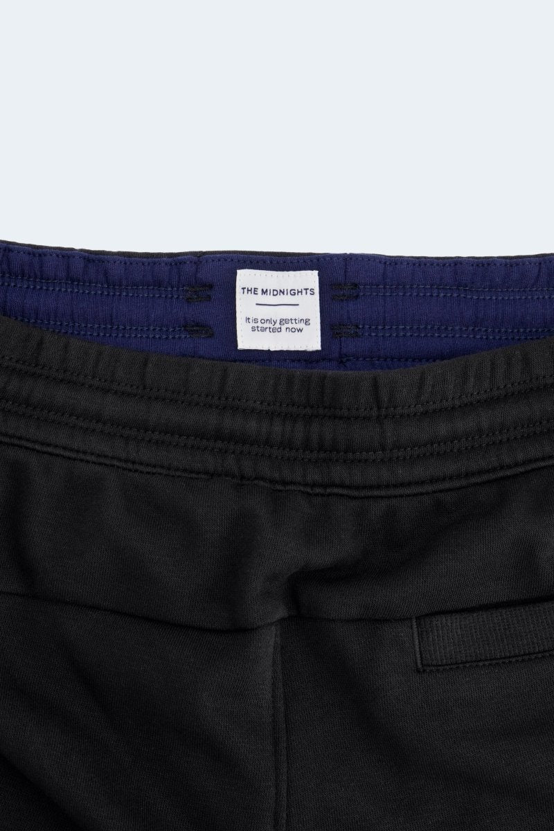 Close-up of Frankster Midnights * The Comfies men's shorts in black cotton with navy blue elastic waistband detailing