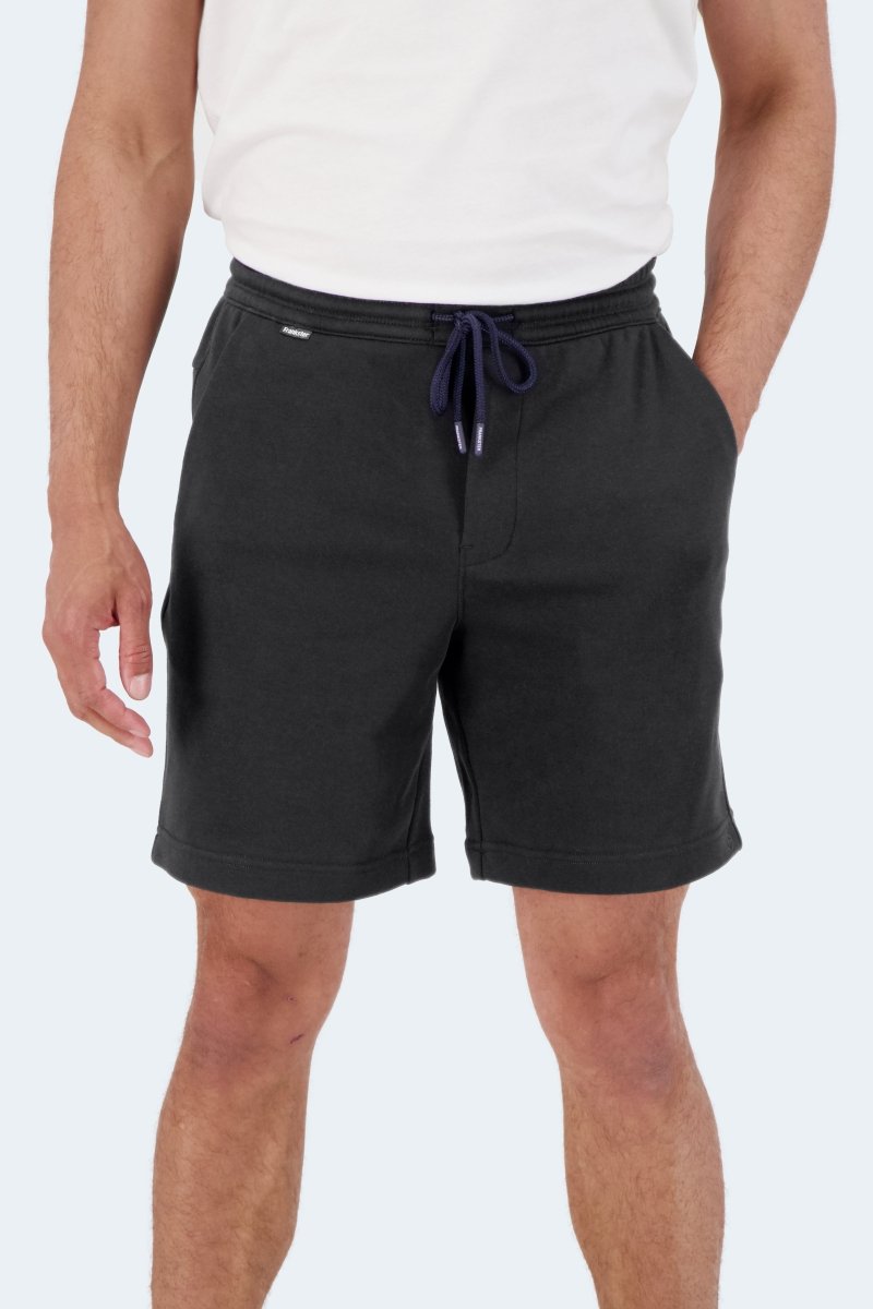 Man wearing black cotton Frankster Midnights * The Comfies men's shorts with drawstring waist standing against white background