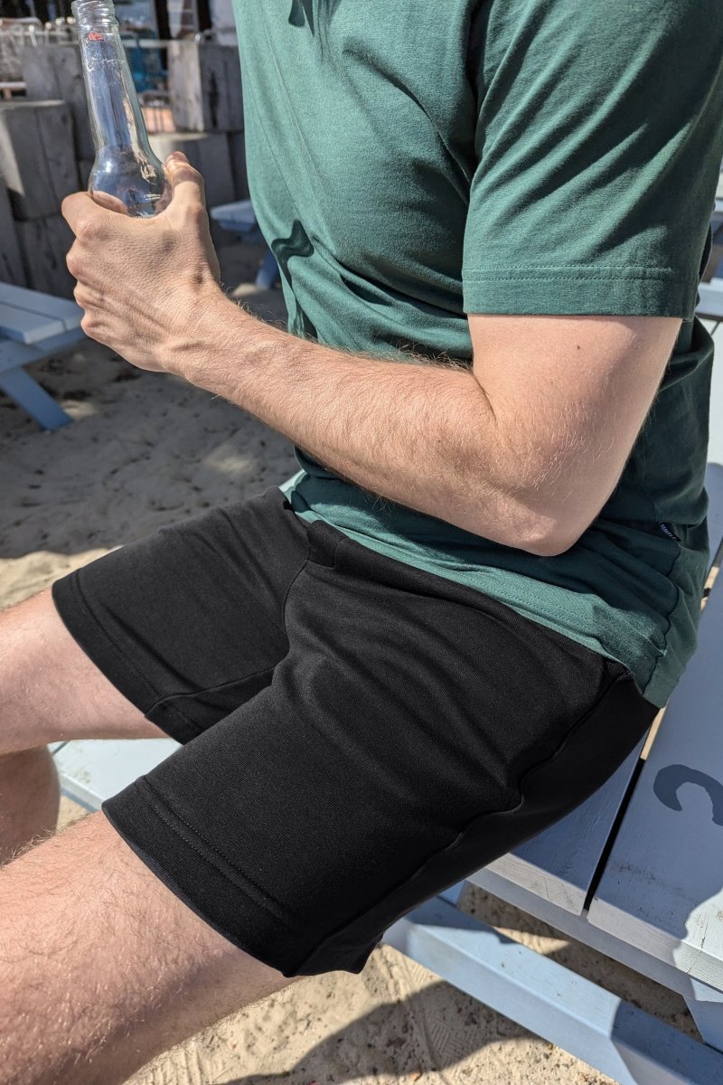 Man wearing black Frankster Midnights * The Comfies men's shorts made of soft cotton fabric sitting outdoors