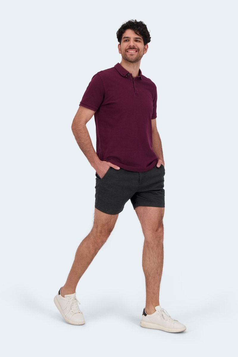 Man wearing Frankster Midnights * The Shorties black stretch cotton men's shorts with a burgundy polo and white sneakers