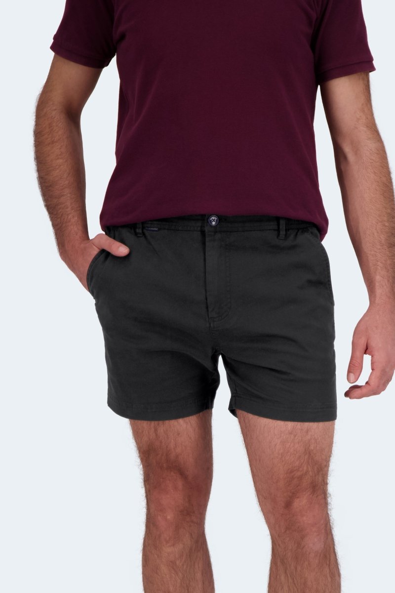 Man wearing Frankster Midnights * The Shorties black stretch cotton men's shorts with a maroon shirt standing with hands in pockets
