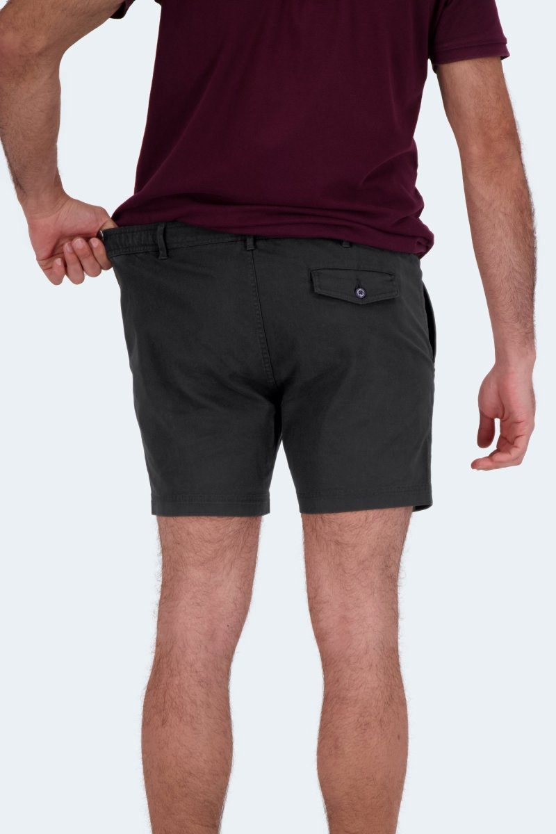 Man wearing black stretch cotton Frankster Midnights * The Shorties men's shorts stretching waistband outdoors