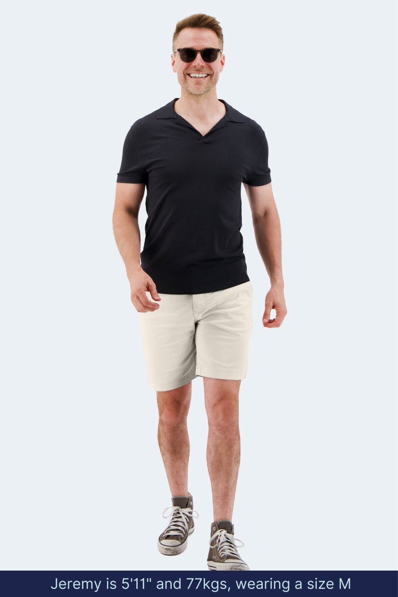 Man wearing off white stretch cotton Mirages * The Everydays men's shorts by Frankster with black shirt and sneakers outdoors