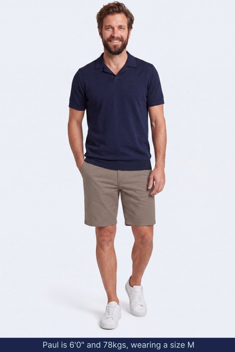Man wearing taupe cotton blend Nomads * The Everydays men's shorts by Frankster paired with navy short sleeve polo and white sneakers in a casual pose