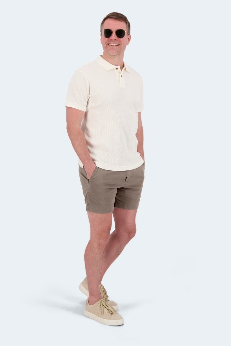 Man wearing Nomads * The Shorties dark khaki stretch cotton men's shorts by Frankster with sunglasses and cream polo shirt