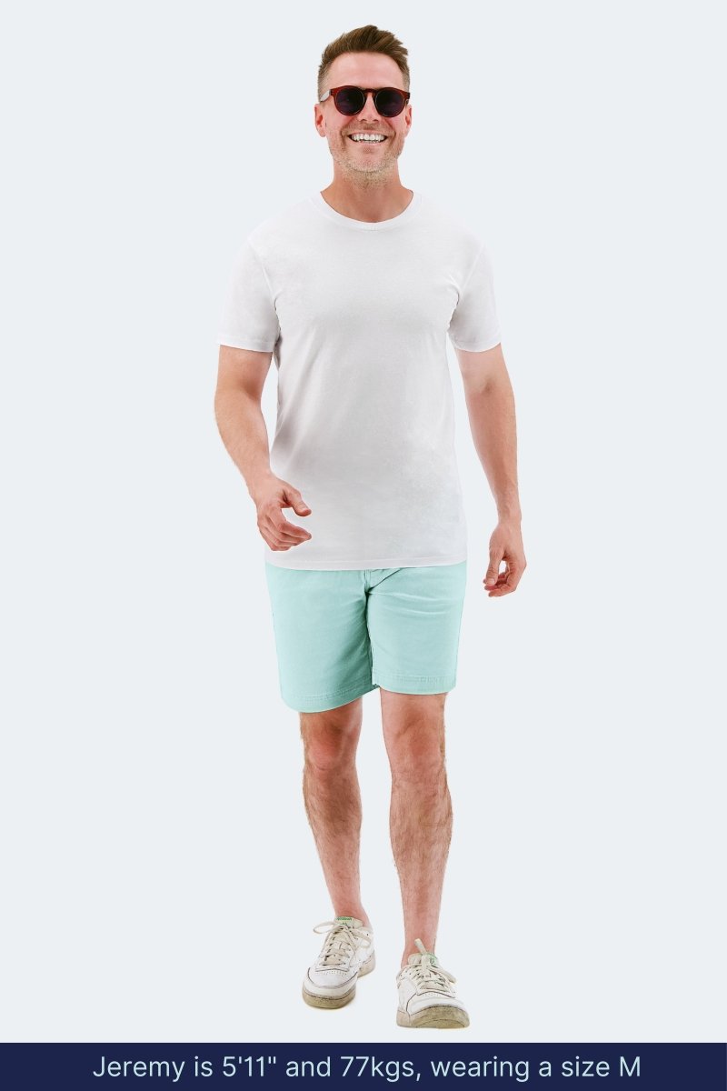 Man wearing light green stretch cotton Rays * The Everydays men's shorts by Frankster with a white t-shirt and sneakers walking outdoors