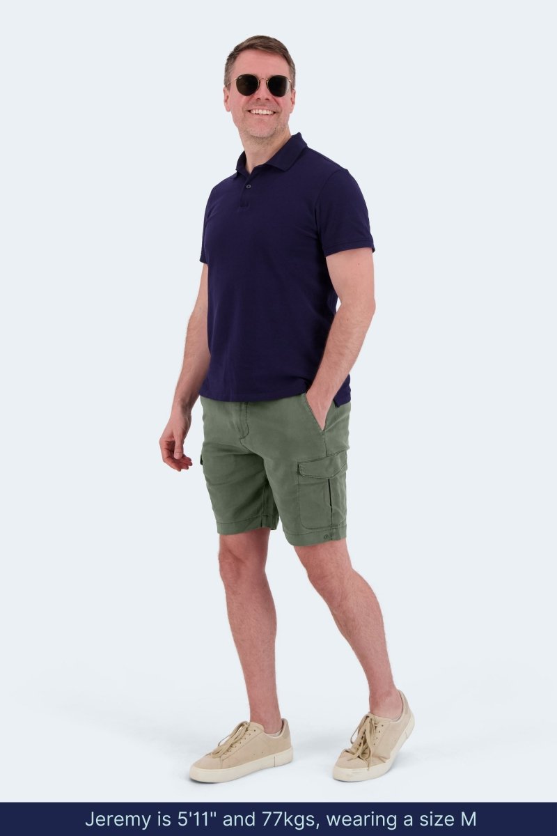 Man wearing Frankster Rebels * The Aussies army green cotton men's cargo shorts with navy polo and beige sneakers