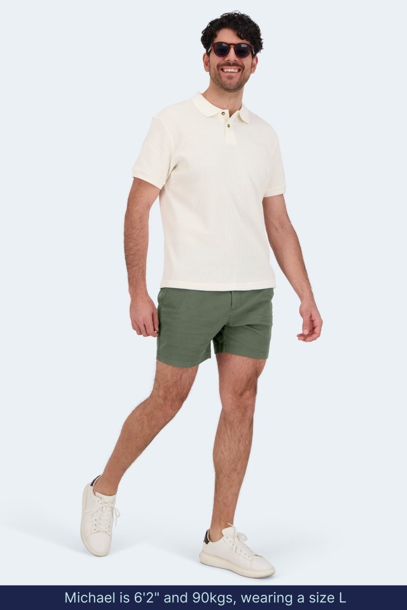 Man wearing olive green cotton stretch Rebels * The Shorties men's shorts by Frankster with white polo and sneakers