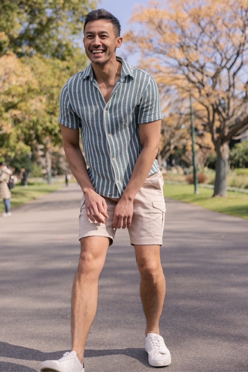 Man smiling outdoors wearing Shores * The Aussies light khaki cotton cargo men's shorts by Frankster with white sneakers