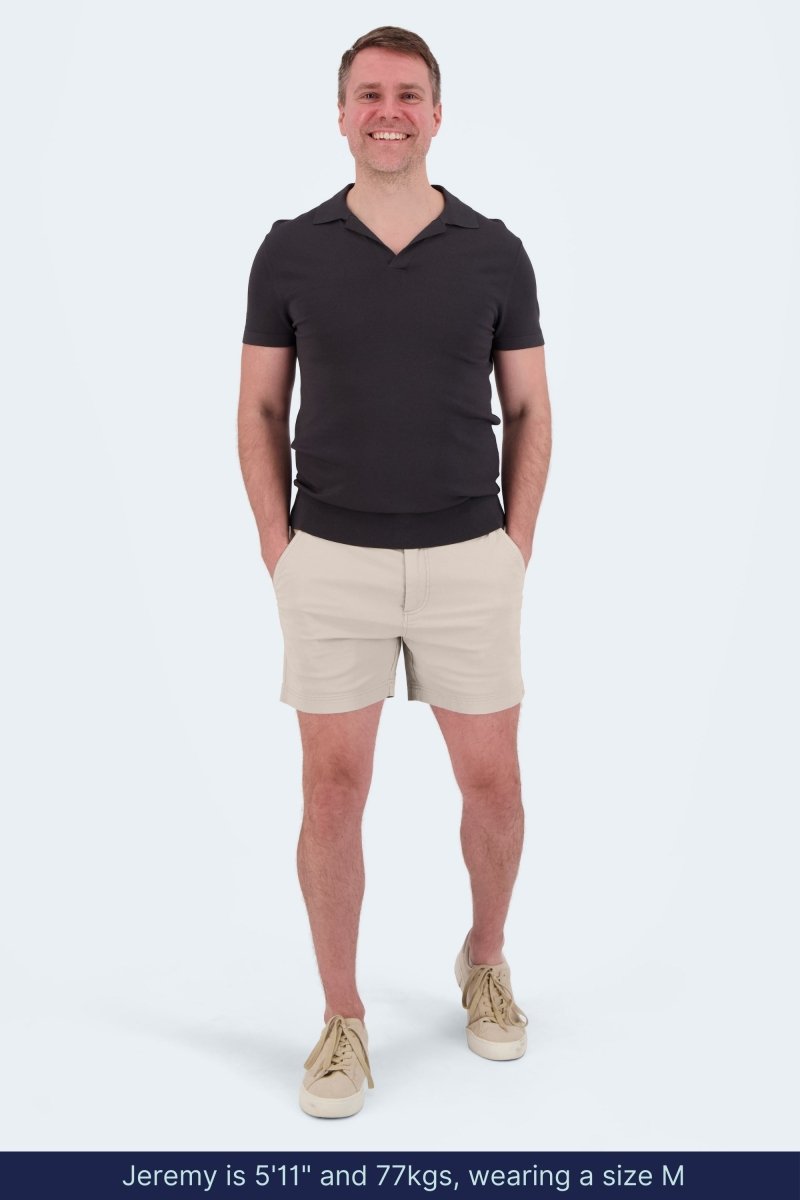 Man wearing Shores * The Shorties light khaki stretch cotton men's shorts by Frankster with a black short sleeve shirt and beige sneakers