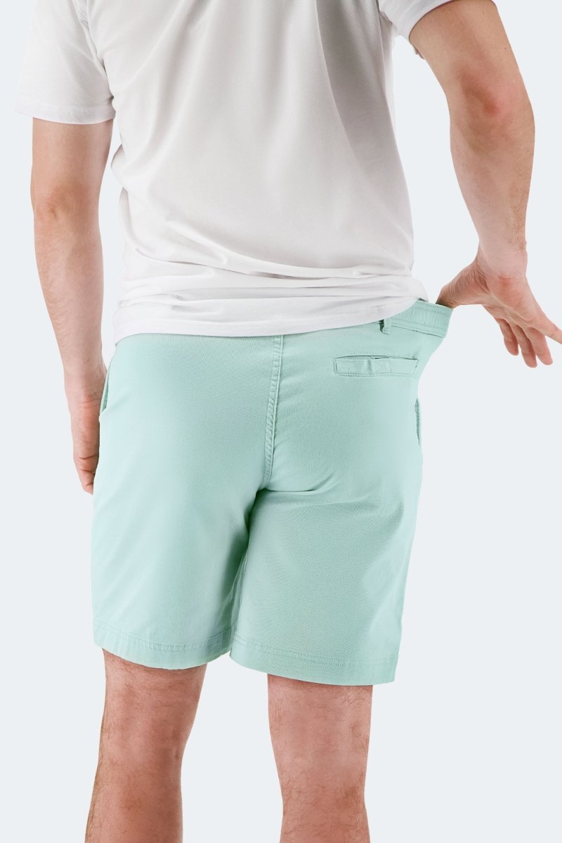 Man wearing light green stretch cotton Rays * The Everydays men's shorts by Frankster pulling waistband outdoors