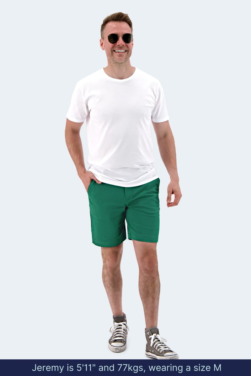 Man wearing Frankster Tropics * The Everydays green stretch cotton men's shorts with white t-shirt and sneakers