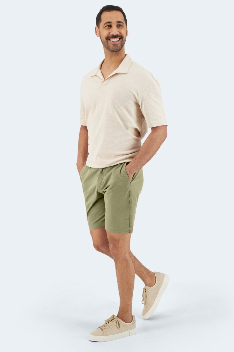 Man wearing Frankster Virgins * The Everydays olive green cotton stretch men's shorts with beige polo and sneakers