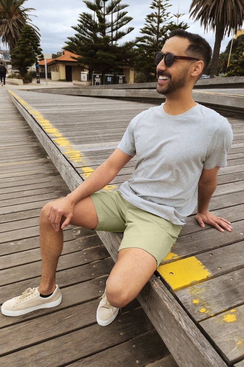 Man wearing olive green cotton stretch men's shorts Virgins * The Everydays by Frankster sitting outdoors on wooden deck