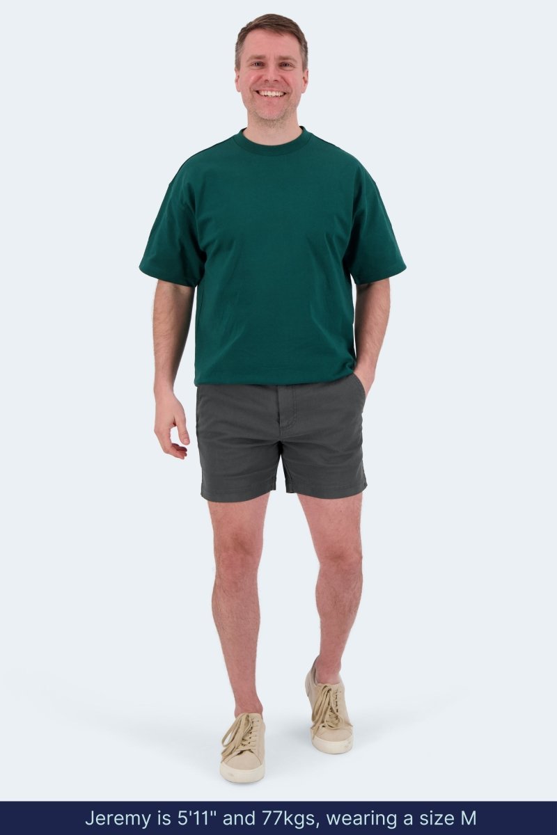 Man wearing Frankster Volcans * The Shorties dark grey stretch cotton men's shorts with casual green t-shirt and beige shoes