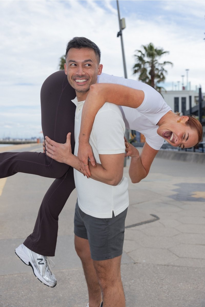 Man wearing dark grey Volcans * The Shorties Frankster stretch cotton men's shorts outdoors with woman on his shoulders