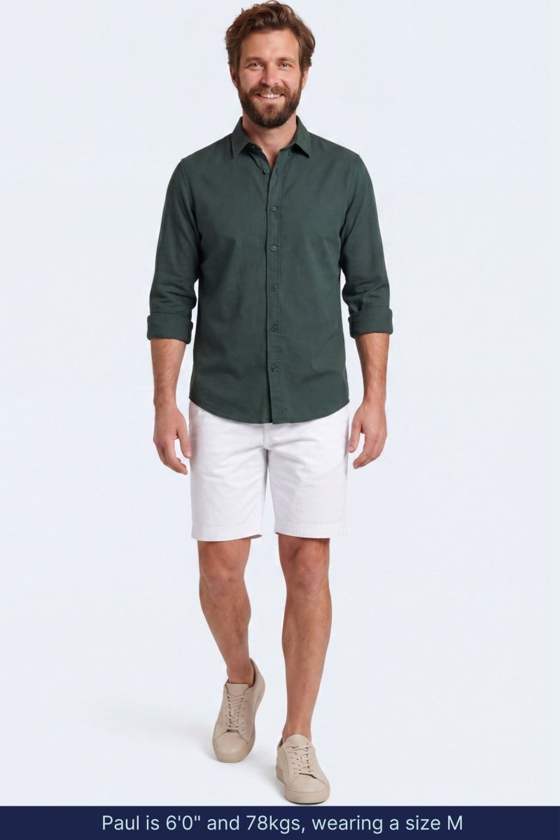 Man wearing white cotton blend Whitecaps * The Everydays men's shorts by Frankster paired with a dark green shirt and beige sneakers, showcasing comfortable and stylish men shorts.